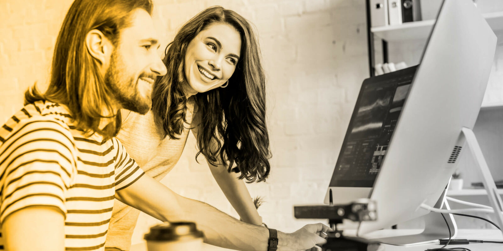 man and woman smiling while looking at a computer and working on ux optimization