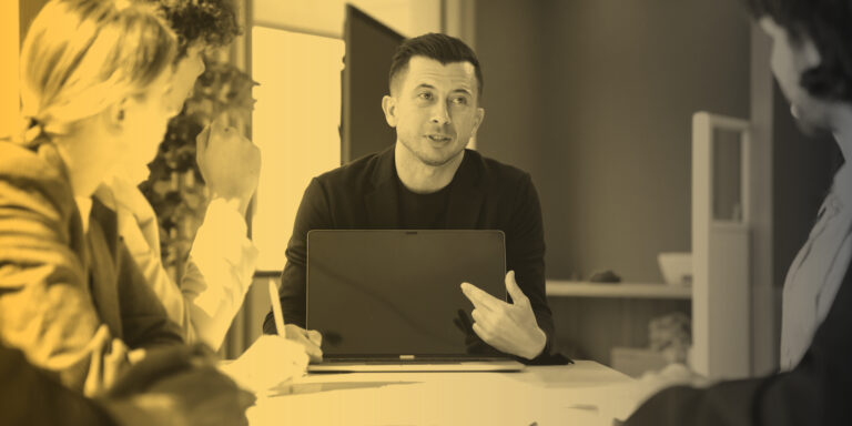Marketing professionals meet with clients at a long table